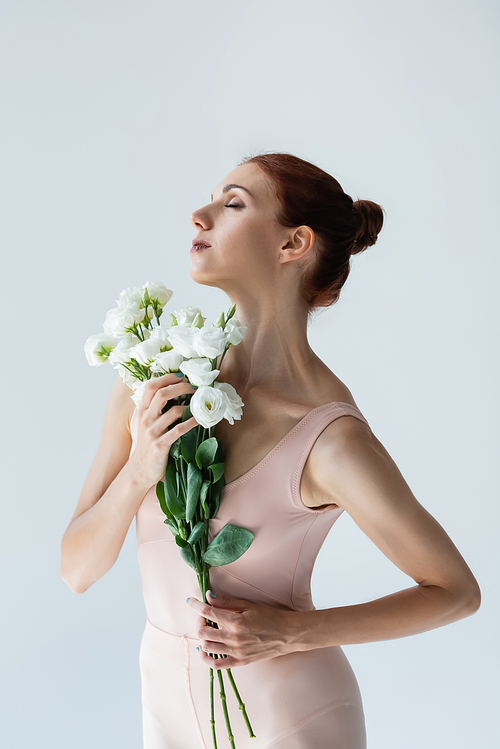 redhead ballerina with closed eyes holding flowers isolated on white