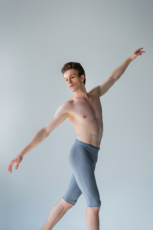 shirtless man with outstretched hands performing ballet dance isolated on gray