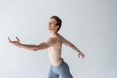 young shirtless ballet dancer performing dance isolated on grey