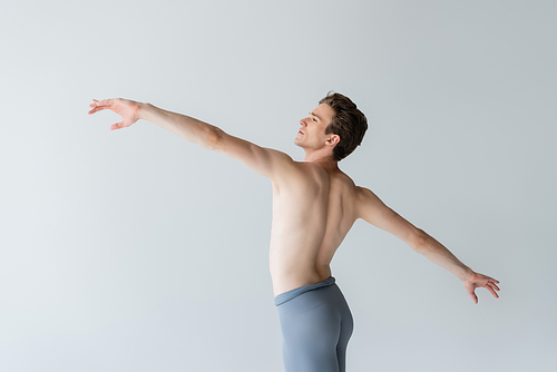 shirtless young man with outstretched hands performing