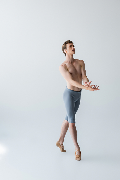 full length of graceful ballet dancer gesturing on grey