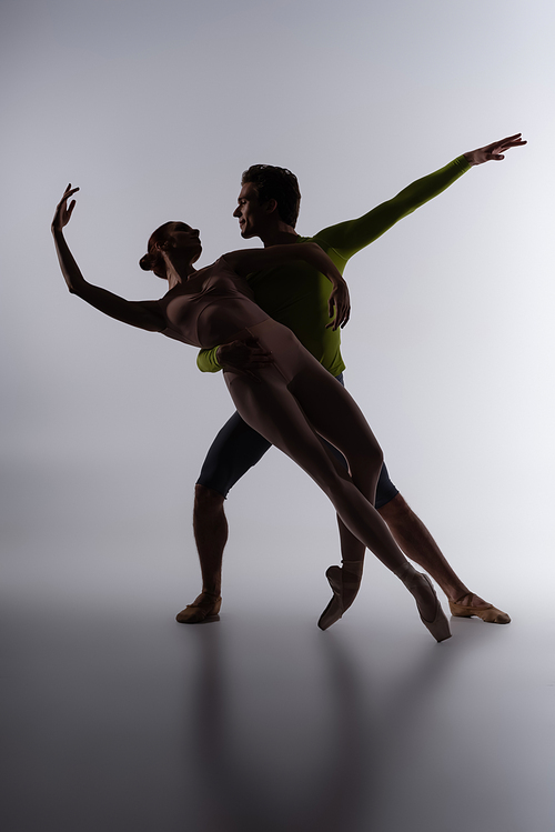 silhouette of ballet dancer supporting ballerina on dark grey