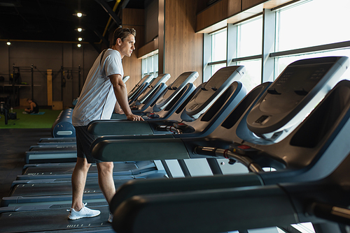 full length view of sportive man standing on treadmill in gym