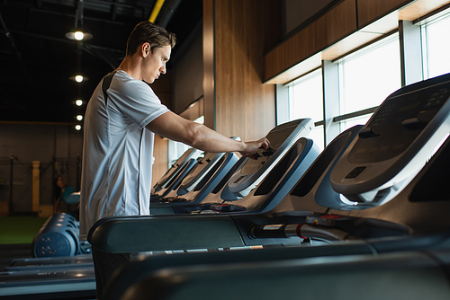 sportsman using touchscreen on treadmill on blurred foreground