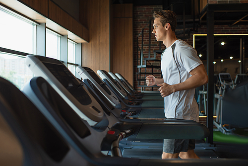 side view of sportsman running on treadmill in gym