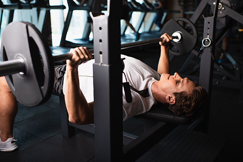 athletic man working out on weightlifting exercising machine in gym