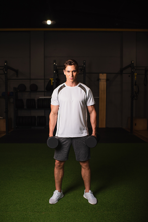 full length view of man with dumbbells  in gym