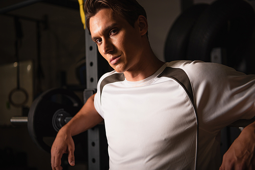 sportive man in t-shirt  near weightlifting exercising machine in gym