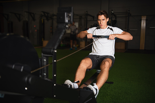 full length view of sportive man training on pull cable exercising machine in sitting position