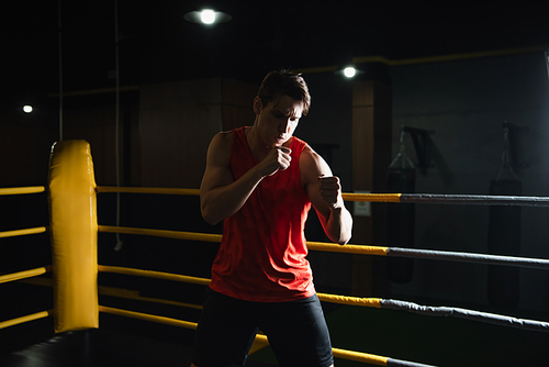athletic man boxing in ring while training in sports center