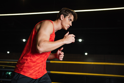 sportive man working out in boxing ring in gym