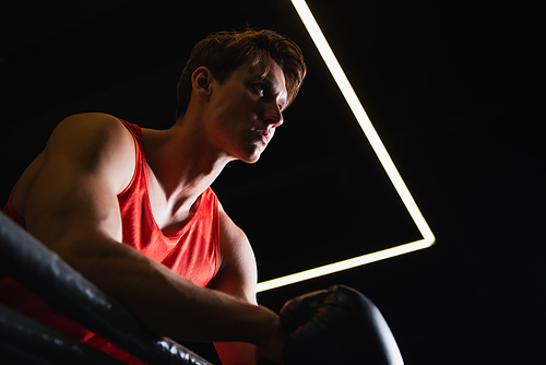 low angle view of sportive man standing in boxing ring and looking away