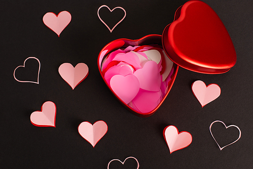 top view of pink paper hearts in metallic box on black