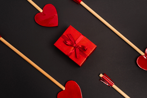 top view of heart-shaped arrows near wrapped present on black