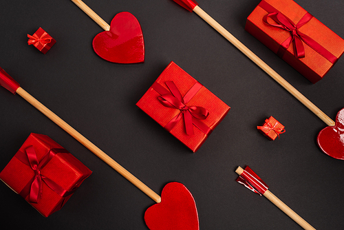 top view of heart-shaped arrows near wrapped presents on black