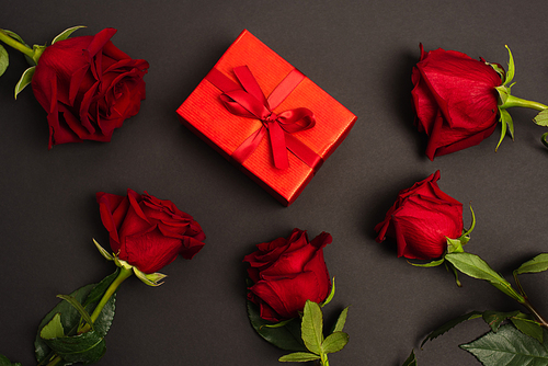 flat lay of red roses near wrapped gift box on black