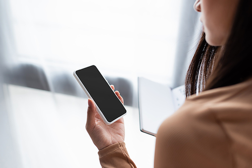 partial view of woman holding mobile phone with blank screen
