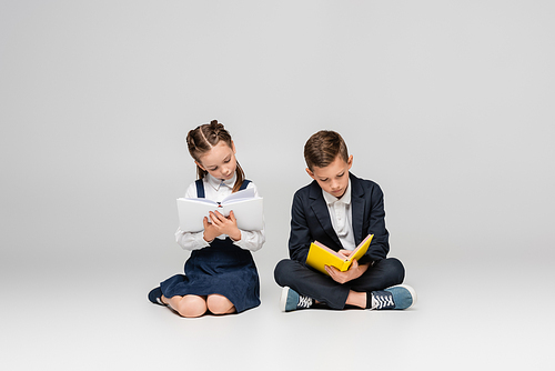 schoolkids sitting and reading books on grey