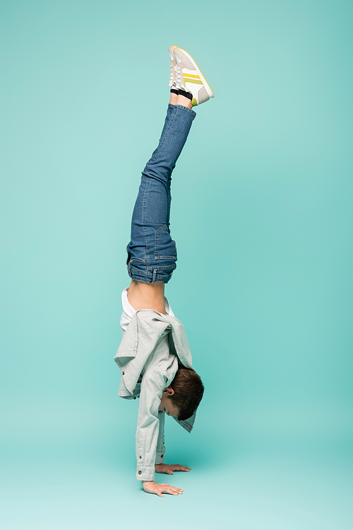 boy in denim jeans doing handstand on blue