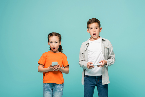 shocked children holding cellphones and  isolated on blue