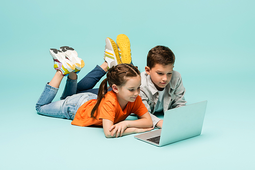 children watching movie on laptop while lying on blue