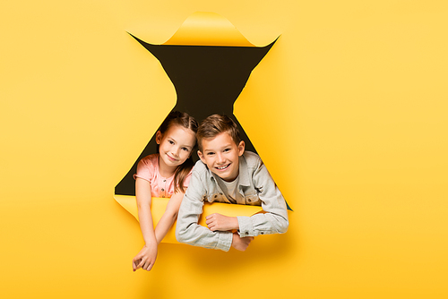 happy kids  through hole on yellow background