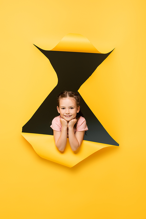 happy girl  through hole on yellow background