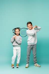 happy kids in sportswear standing with tennis rackets on blue