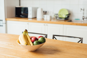 Selective focus of ripe fruits on wooden table in kitchen