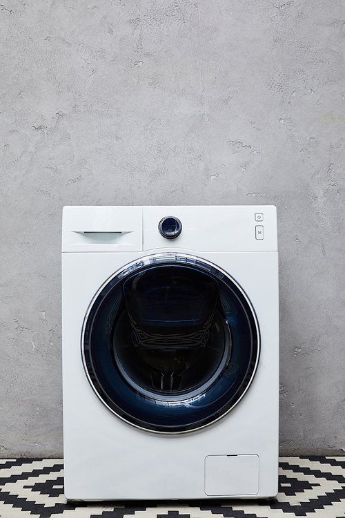 washing machine near grey wall in bathroom