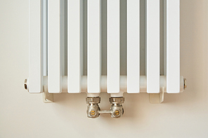 white and modern heating radiator near wall in apartment