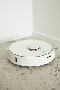 modern robotic vacuum cleaner washing floor tiles near white walls