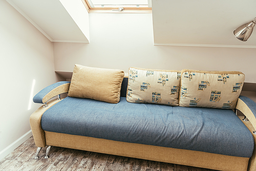 cozy attic room with window, and comfortable sofa with pillows