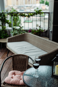 Glasses of wine on table near wicker sofa on terrace