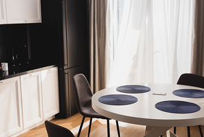 smartphone on dining table near modern chairs