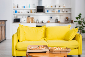 delicious pizza on table near yellow sofa in modern kitchen