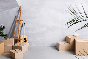 carton boxes near easel, acoustic guitar and plants