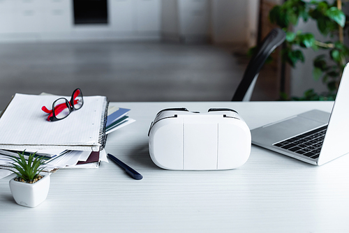 vr headset, laptop, notebooks and eyeglasses on table