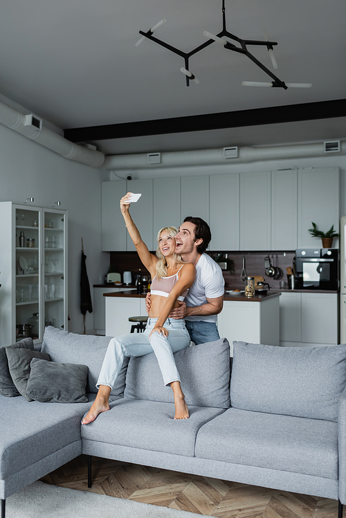 happy woman taking selfie with boyfriend in living room