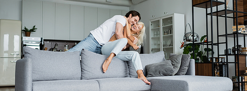 cheerful young couple having fun in living room, banner