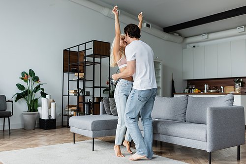 woman raising hands while dancing with boyfriend in living room
