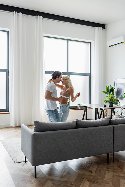 happy couple dancing near grey couch in living room