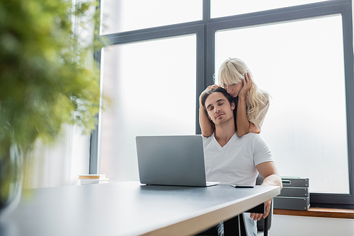 blonde woman stroking hair of pleased boyfriend working from home