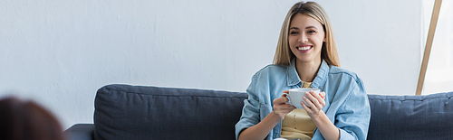 smiling woman holding cup of tea during conversation with psychologist, banner
