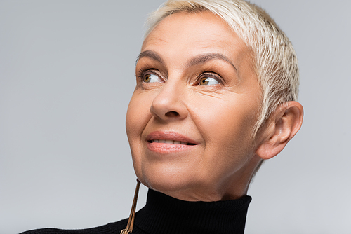smiling senior woman with long earring and black turtleneck isolated on grey