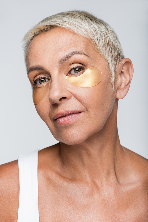 senior woman with collagen eye patches isolated on grey