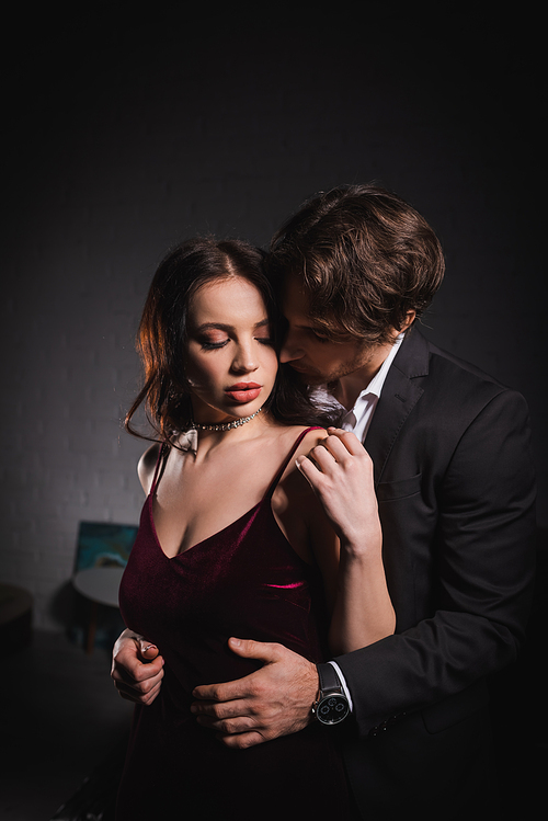 young man seducing pretty young woman in elegant dress in bedroom at night