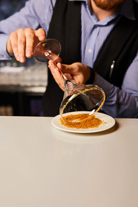 cropped view of bearded barman holding margarita glass near saucer with brown sugar