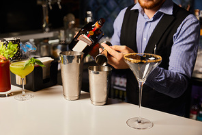 cropped view of bartender preparing cocktails in bar