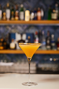 margarita glass with sweet orange cocktail on bar counter